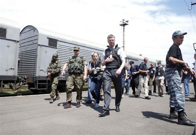 Monitors from the Organization for Security and Cooperation in Europe walk near a train at a railway station in the town of Torez, Ukraine, on Sunday. Employees and local residents say it contains bodies of passengers of the crashed Malaysia Airlines Boeing 777.