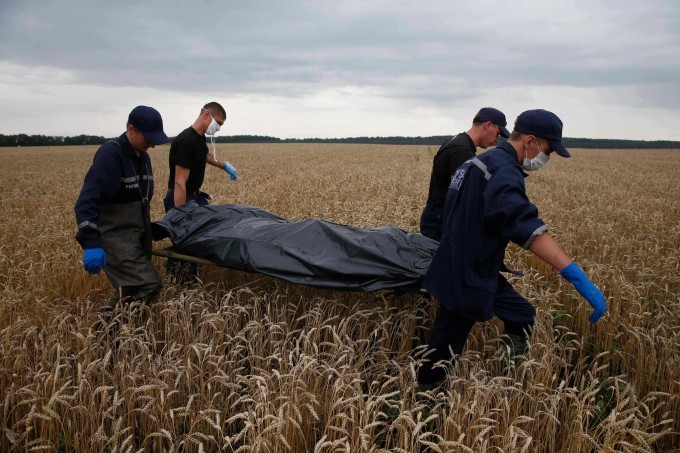 Emergency workers on Saturday carried a body from the site of the Malaysia Airlines Flight 17 crash in the Donetsk region. For many, the disaster brought home a struggle that had seemed distant. Photo: Maxim Zmeyev/Reuters