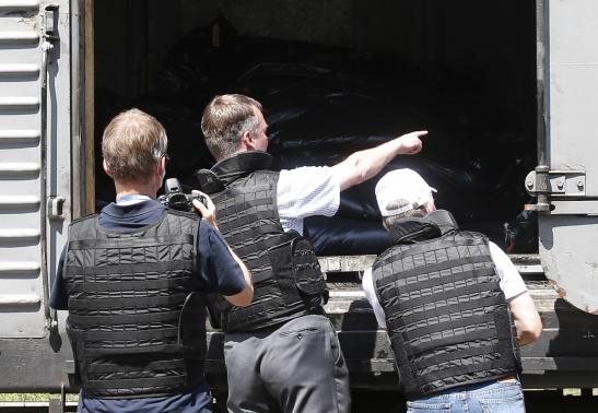 Monitors from the Organization for Security and Cooperation in Europe inspect a refrigerator wagon, which according to employees and local residents contains bodies of passengers of the crashed Malaysia Airlines Boeing 777 plane, at a railway station in the town of Torez, Donetsk region July 20, 2014. REUTERS/Maxim Zmeyev