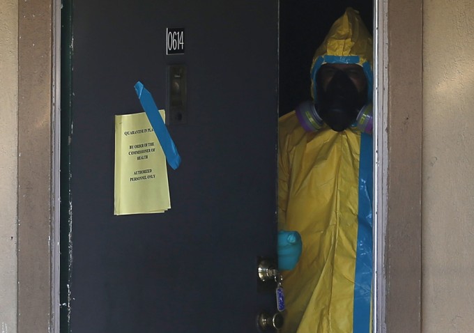  A worker in a hazardous material suit looks out from the apartment unit where a man diagnosed with the Ebola virus was staying in Dallas, Texas, October 5, 2014. [REUTERS]