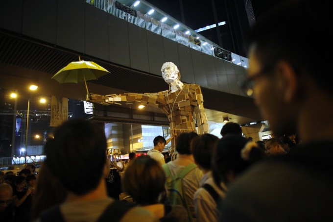 Protesters install a statue with a yellow umbrella as other demonstrators block the main street to the financial Central district outside of the government headquarters building in Hong Kong October 5, 2014. [Reuters]