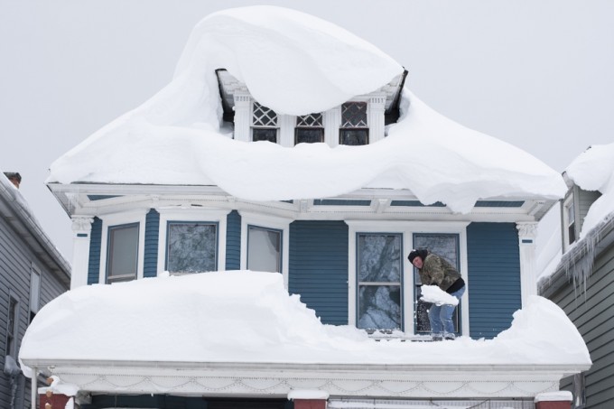 Tom Wilczak shovels snow from the roof of his home following a storm in Buffalo, New York November 20, 2014.   REUTERS/Aaron Lynett