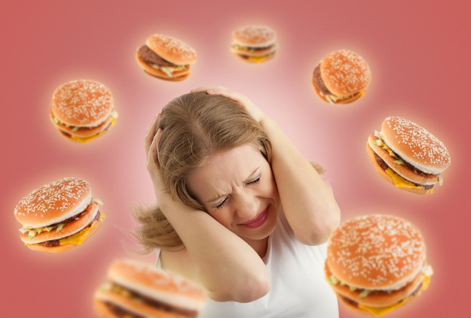 Photo: "Diet concept. frightened girl in the stress and flying around the burgers on a red background." Evgeny Atamanenko for Shutterstock.