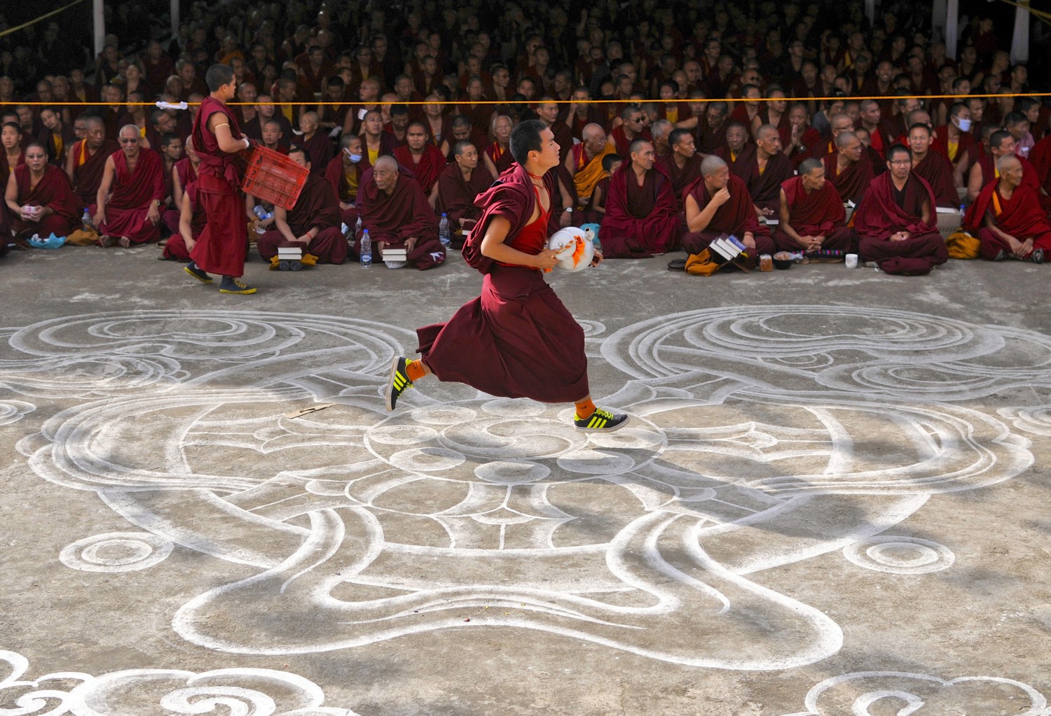 A young Buddhist monk runs past other monks to fetch butter tea to be served to attendees of the Jangchup Lamrim teachings conducted by the exiled Tibetan spiritual leader the Dalai Lama (unseen) at the Gaden Jangtse Thoesam Norling Monastery in Mundgod in the southern Indian state of Karnataka December 25, 2014. REUTERS/Abhishek N. Chinnappa (INDIA - Tags: RELIGION) - RTR4J8CD