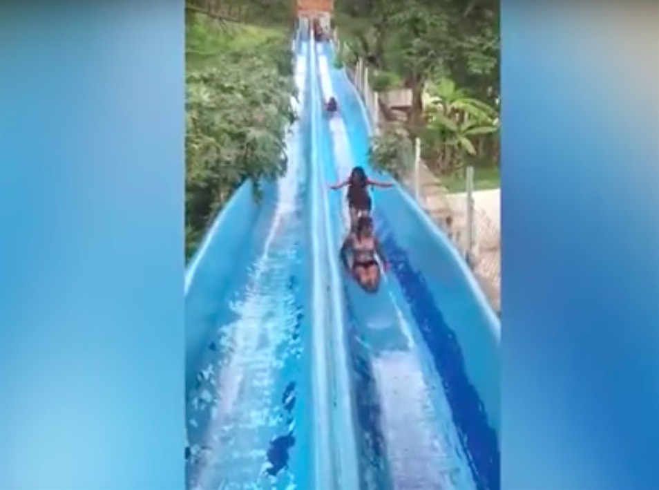 Watch Two young women stuck in middle of waterslide get slammed by a