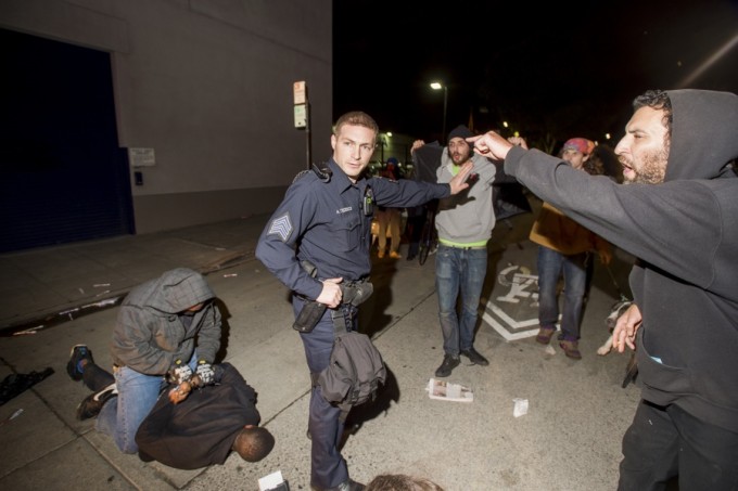 A police officer holds back anti-police demonstrators as an undercover officer makes an arrest in Oakland, California December 10, 2014. More than 100 protesters gathered for a fifth consecutive night of demonstration. REUTERS/Noah Berger 