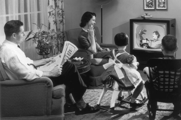 A-family-sits-in-their-living-room-watching-a-childrens-television-programme