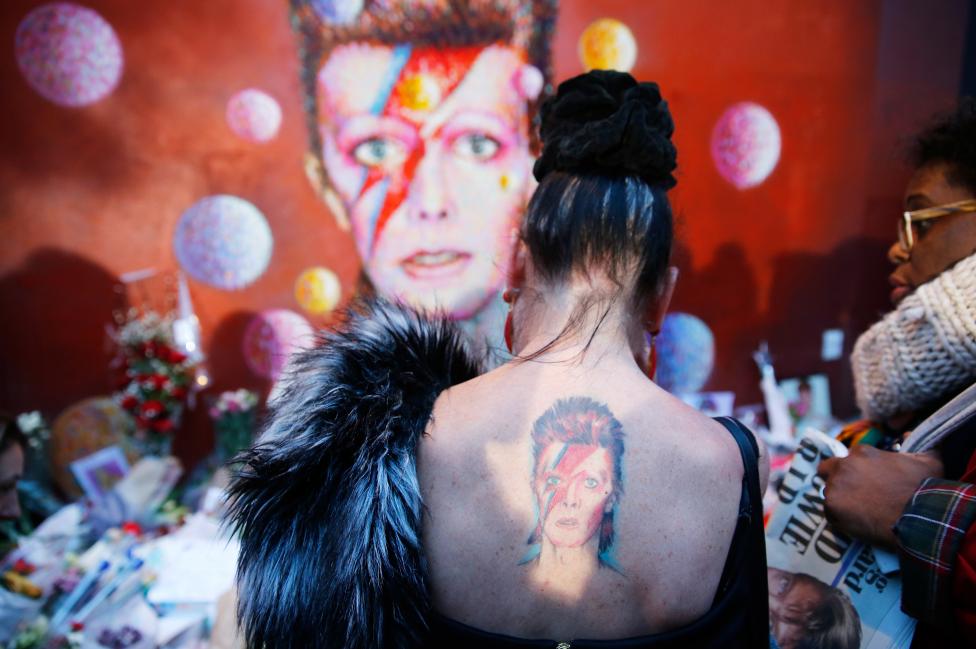 A woman with a Ziggy Stardust tattoo visits a mural of David Bowie in Brixton, south London, January 11, 2016. REUTERS