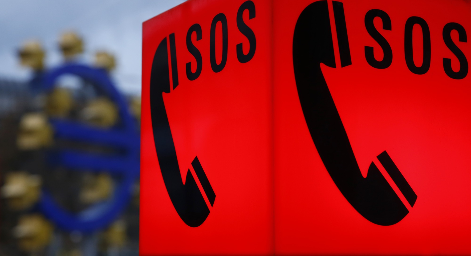 An emergency phone sign is seen next to the euro sculpture outside headquarters of the European Central Bank  in Frankfurt