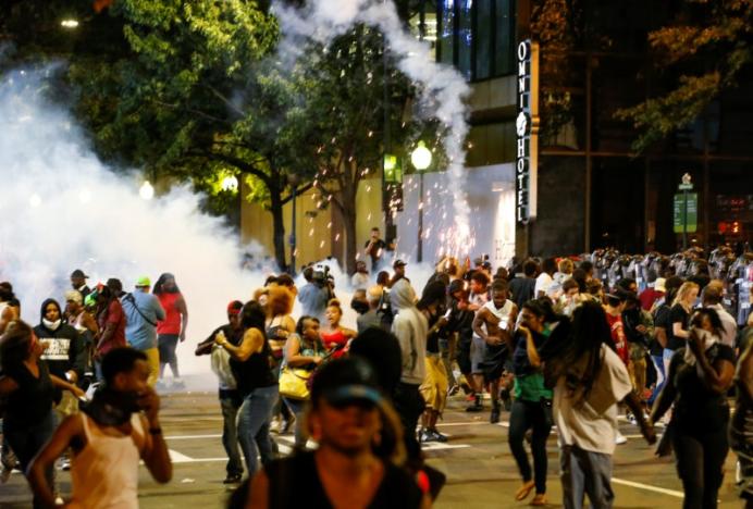 People run from flash-bang grenades in uptown Charlotte during a protest of the police shooting of Keith Scott. REUTERS/Jason Miczek